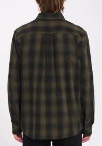 Langærmet flannel skjorte med et mørkegrønt og sort ternet mønster, lavet af tekstureret stof, med knapmanchetter og en yoke-design.