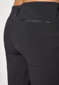 Melnas bikses ar elegantu dizainu, kuru aizmugurē ir kabata ar rāvējslēdzēju un gluda tekstūra. Pielāgota fit uzsver siluetu, nepārslogojot ar lieku materiālu.