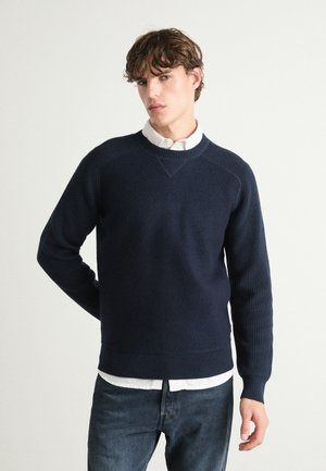 Maglione a maglia blu navy con maniche e orlo a coste, caratterizzato da un collo rotondo e dettagli testurizzati sulle spalle.