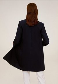 Námořnický oversize blazer s rovnými liniemi, dlouhými rukávy a mírně rozšířeným zadním dílem. Hladká textura, minimální detaily a žádné viditelné kovové prvky.