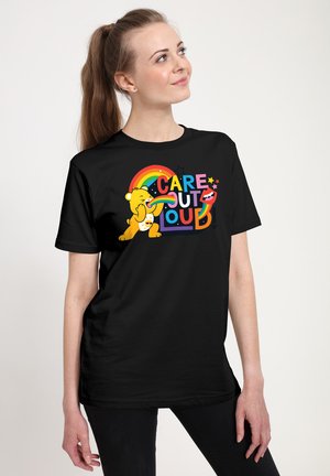 Sort bomulds t-shirt med et farverigt grafisk billede af en bjørn og teksten "CARE OUT LOUD," akkompagneret af en regnbue og stjerner.