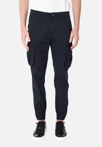 Pantaloni cargo navy con polsini elasticizzati, due tasche laterali e dettagli in bottone. Il materiale sembra leggero con una texture liscia. Abbinati a sneaker nere.