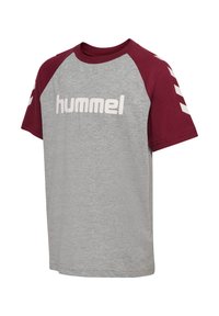 T-shirt en coton gris avec des manches raglan bordeaux, arborant le logo "hummel" blanc et un motif en chevrons sur les manches. Coupe décontractée, design à col rond.