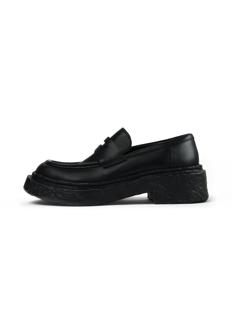 Black leather loafer with a rounded toe, prominent stitching, and a thick, textured black platform sole. Smooth finish with a minimalist design.