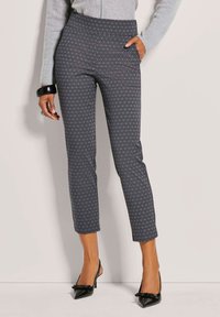 Gevoerde donkergrijze broek met een subtiele geometrische print, voorzien van een hoge taille en een slim fit, gecombineerd met zwarte stilettohakschoenen.