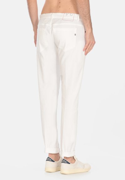 I pantaloni in denim bianco presentano tasche posteriori, una vestibilità dritta e orli risvoltati. Indossati con sneakers di colore chiaro. Design semplice, senza motivi.