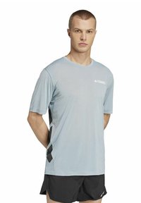 Camiseta atlética de color azul claro con mangas cortas, cuello redondo y acentos laterales negros. Fabricada con tejido transpirable para el uso activo.