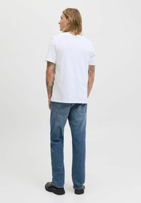 Vit bomull T-shirt med rund halsringning, kombinerad med blå denimjeans. Outfitten har en avslappnad passform och är helfärgad utan mönster.