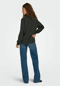 Mörkgrå långärmad topp med krage, matchad med högmidjade blå jeans. Tyget ser mjukt ut med en avslappnad passform och flödande ärmar.