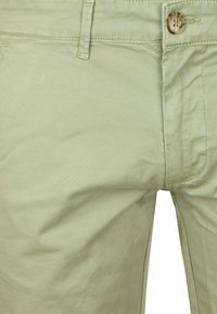 Lichtgroene katoenen broek met een gladde textuur, voorzien van een knoopsluiting en gestikte naden. Geen zichtbare zakken in deze close-up.