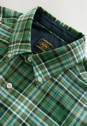 Groen en blauw geruit shirt met een button-down kraag, voorzien van een label met de tekst "NEXT" en twee witte knopen aan de voorkant.