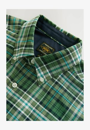 Grüne und blaue kariertes Hemd mit Button-down-Kragen, versehen mit einem Etikett mit der Aufschrift "NEXT" und zwei weißen Knöpfen auf der Vorderseite.