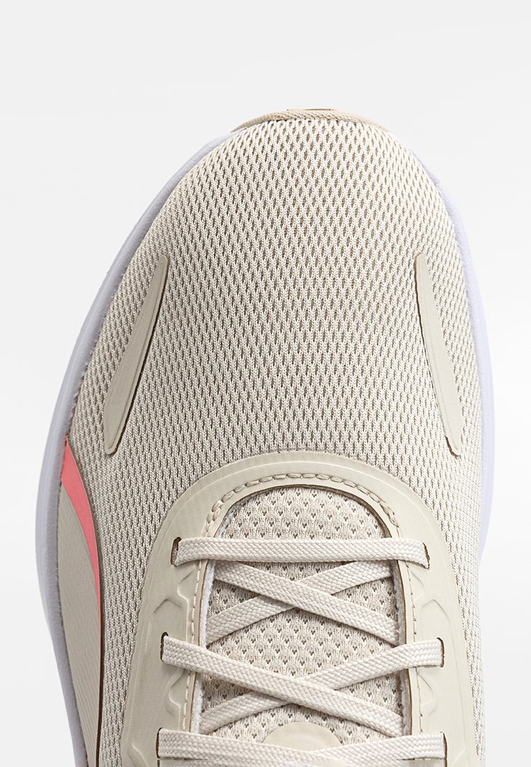 Chaussure de sport légère avec une tige en mesh beige, une bande rose contrastante et une semelle blanche. Présente un lacet texturé et un design épuré.