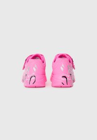 Sneakers rosa brillante con una parte superiore in sintetico liscio, dotati di una cinghia in velcro e accenti decorativi neri sul tallone. Elemento di ammortizzazione testurizzato.