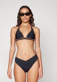 Juodas bikini, kurio trikampio formos viršutinė dalis su oranžiniais akcentais ir aukšto liemens apačia su V formos iškirpte. Lygus paviršius, minimalistinis dizainas, be raštų.