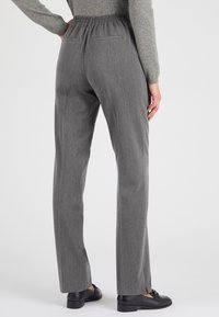 Grijze, op maat gemaakte broeken met een ontspannen elastische tailleband, twee achterzakken en een recht zulend ontwerp. De stof heeft een subtiele textuur.