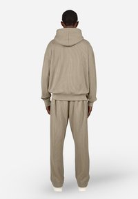 Beige ribbet hettegenser og matchende bukser. Løs passform, teksturert stoff, kängurulomme og justerbar hette. Elastiske mansjetter og midjebånd.