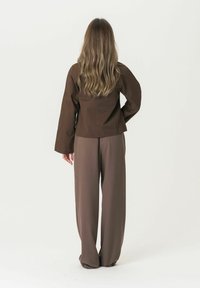 Brown fitted top with long sleeves paired with wide-leg brown trousers. Smooth, textured fabric; minimalistic design without patterns.