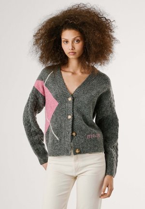 Grijze gebreide cardigan met een V-hals, voorzien van een roze abstract ontwerp en witte accenten. Het heeft houten knopen en gestructureerde mouwen.