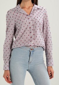 Camicia button-up in tessuto leggero con un motivo a righe bianche e rosse, caratterizzata da piccoli motivi floreali rossi. Maniche lunghe con colletto classico.