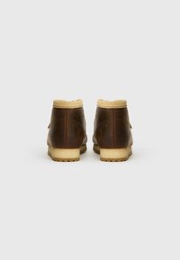 Brown leather ankle boots with a tan fleece lining, rounded shape, and textured sole. Back view shows stitching and minimal hardware details.