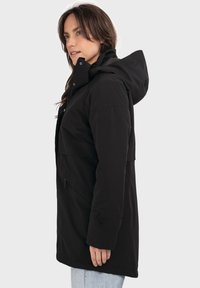 Schwarze wasserdichte Jacke mit Kapuze, ausgestattet mit einem Reißverschluss vorne, Seitentaschen und einer etwas lockeren Passform. Glatter Stoff und minimalistisches Design.
