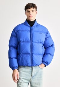 Ryškiai mėlynas pūkinis blynas su stovinčia apykakle, siuvinėta konstrukcija, bangomis siūtos rankoves ir priekiniais užtrauktukais. Išsiuvinėtas logotipas ant krūtinės.