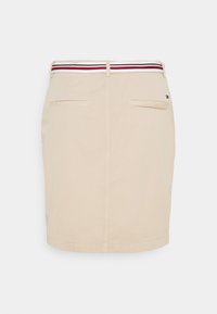 Beżowa spódnica o prostym kroju, z paskiem w czerwono-biało-niebieskie paski. Zawiera dwie tylne kieszenie i minimalne przeszycia.