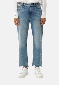 Jeans azules de cintura alta con un diseño de pierna recta, dobladillo deshilachado y detalles de desvanecimiento, combinados con zapatillas blancas.