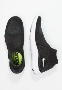 Chaussures de sport en tricot noires avec des sangles entrecroisées et une semelle blanche. L'intérieur arbore un texte vert vif. Logo Nike sur le côté.