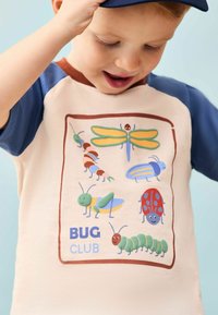 Kinder Kurzarmshirt mit beigem Körper und blauen Ärmeln. Die Vorderseite zeigt ein buntes Grafikdesign mit Cartoon-Insekten und dem Text "BUG CLUB" in Blau.