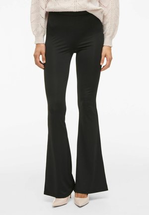 Pantalons évasés noirs en matériau lisse et extensible ; taille haute, ajustés aux cuisses, s'évasant à partir du genou. Aucun motif visible.