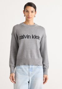 Hallhalli hallide särk musta "calvin klein" logoga ees, ümmargune kaelus, soonikkoes varrukad ja hem, kantud helesiniste teksadega.