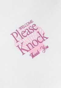 Άσπρο ύφασμα με ροζ σχέδιο κοχυλιού και μοβ κείμενο που λέει «Καλώς ήρθατε, παρακαλώ χτυπήστε, ευχαριστώ», τοποθετημένα διαγώνια.