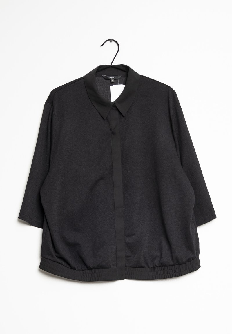 Sort oversized skjorte med knapper og krave, korte ærmer og elastisk bundkant, lavet af tekstureret stof. Hængende fra en krog.