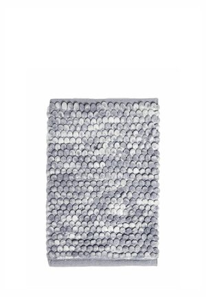 Tapis de bain texturé gris et blanc avec un motif pompon doux et rond et une bordure cousue sur fond blanc.