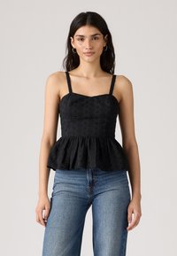 Svart peplum topp med tynne stropper, med teksturert blomsterbroderi. Stoffet har en glatt finish som komplementerer høyt liv bukser.
