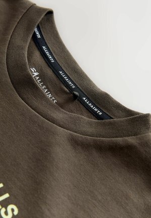 Brun bomull T-shirt med rund halsringning, som har ett strukturerat tyg och en logotags inuti kragen. Enkelt design, utan mönster.