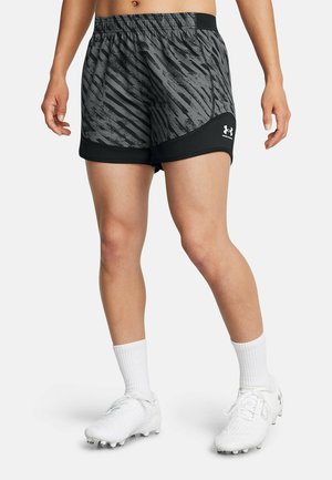 Graue und schwarze Sportshorts mit einem strukturierten Muster und elastischem Bund, kombiniert mit weißen Socken und Fußballschuhen.