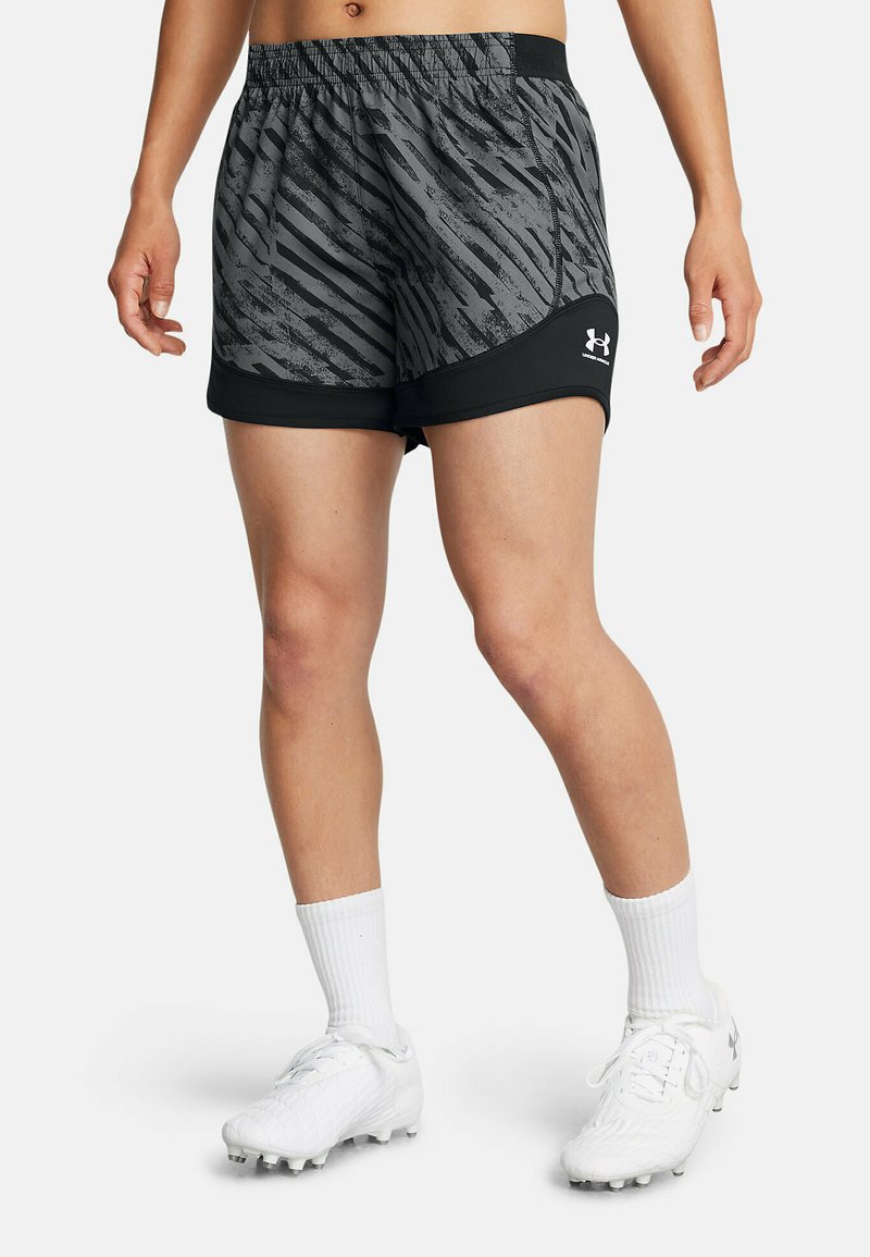 Grå och svarta sportshorts med ett strukturmönster och elastisk midja, som kombineras med vita strumpor och fotbollsskor.