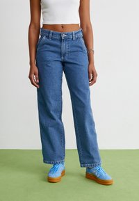 Šviesiai mėlyni, aukšta juosmens džinsai su tiesia kelių linija. Lygus paviršius su subtiliu nusidėvėjimu, turi priekines kišenes ir sagčių uždarymą.