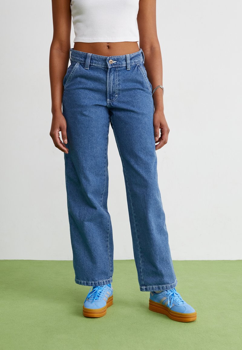 Šviesiai mėlyni, aukšta juosmens džinsai su tiesia kelių linija. Lygus paviršius su subtiliu nusidėvėjimu, turi priekines kišenes ir sagčių uždarymą.