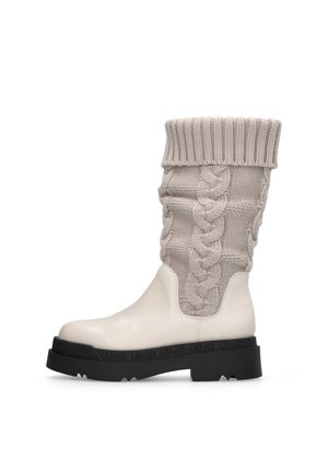 Stivale in pelle bianco sporco con suola nera spessa e parte superiore in maglia beige con motivo a trecce e risvolto piegato.