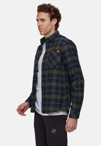 Camicia di flanella a quadri blu navy e verde, con un design a bottoni, due tasche sul petto e una piccola etichetta con logo sul lato sinistro del petto.