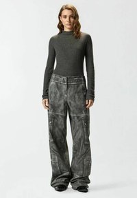 Maglione grigio a collo alto a coste abbinato a pantaloni cargo grigi oversize con dettagli a cucitura, tasche multiple e design a gamba larga.