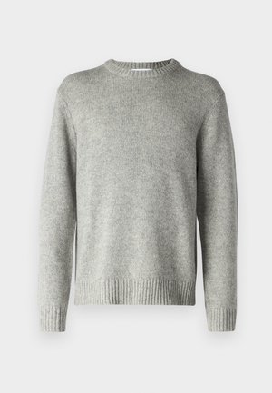 Pelēks adīts džemperis ar apaļu kakla izgriezumu, ribotām piedurknēm un apakšmali, kā arī mīkstu tekstūru. Nav redzami raksti vai aksesuāri.