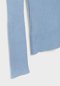 Manche et ourlet à bord-côtes bleu clair avec poignets évasés sur fond blanc.