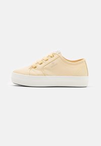 Gelbe Canvas-Sneaker mit weißer Gummisohle, runder Zehenpartie, Schnürdesign und subtiler Logo-Stickerei an der Seite. Glatte Textur insgesamt.