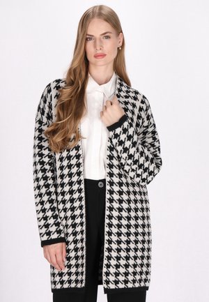 Cardigan in bianco e nero a motivo pied de poule, realizzato in tessuto lavorato a maglia, caratterizzato da una vestibilità comoda, maniche lunghe e un design aperto sul davanti.