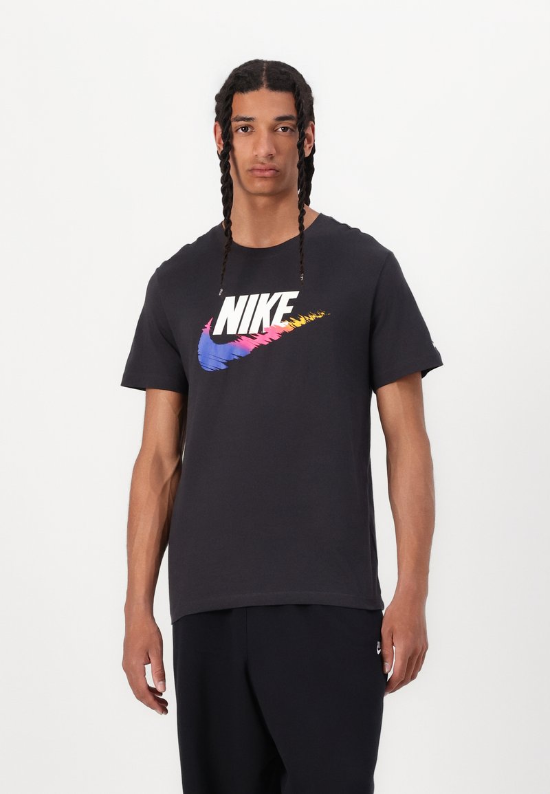 Juodas medvilninis marškinėlis su dideliu, daugiaspalviu Nike logotipu krūtinėje. Trumpomis rankovėmis ir klasikinėmis apvalios iškirptės.